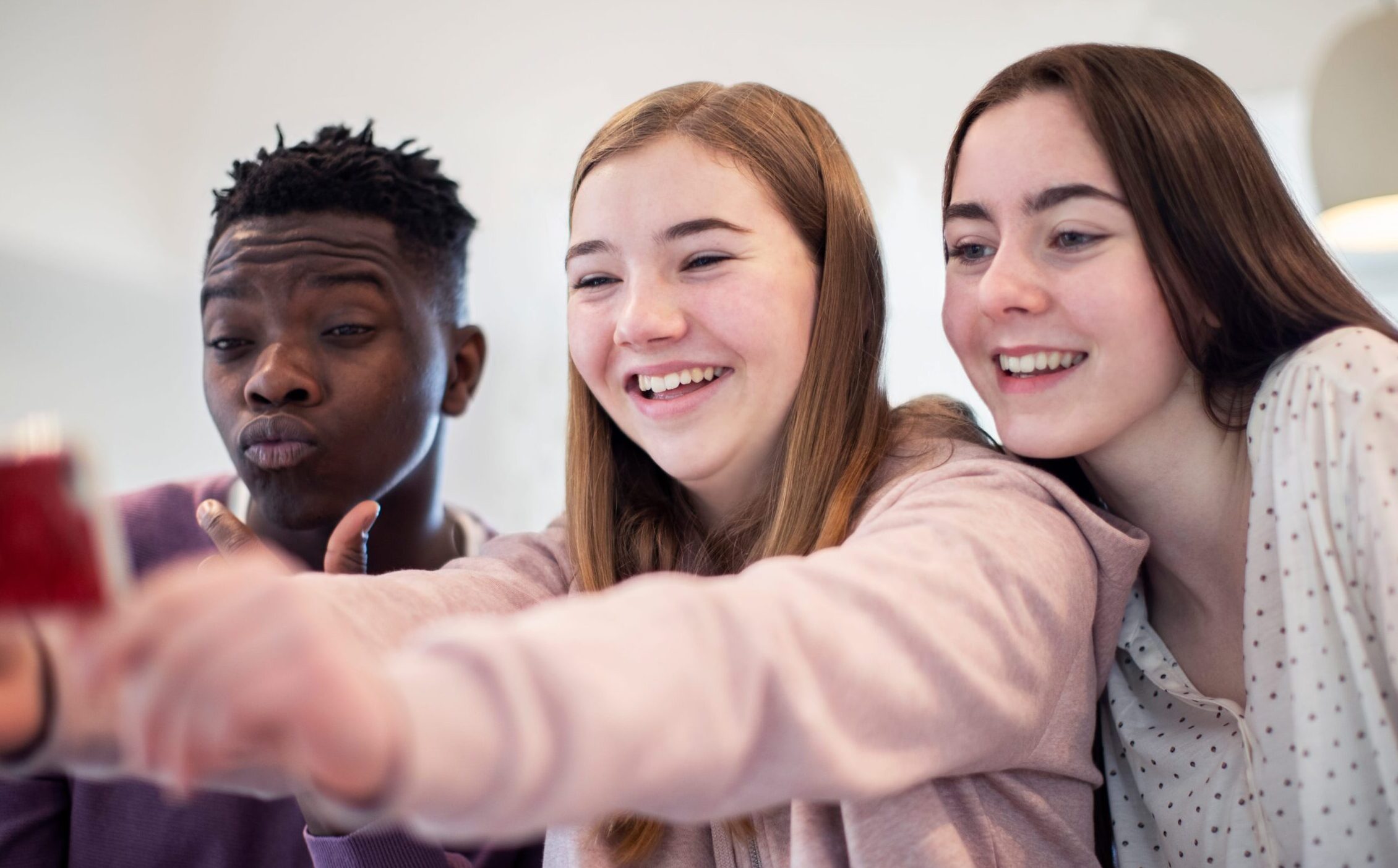 A group of teenagers posing and smiling for a selfie
