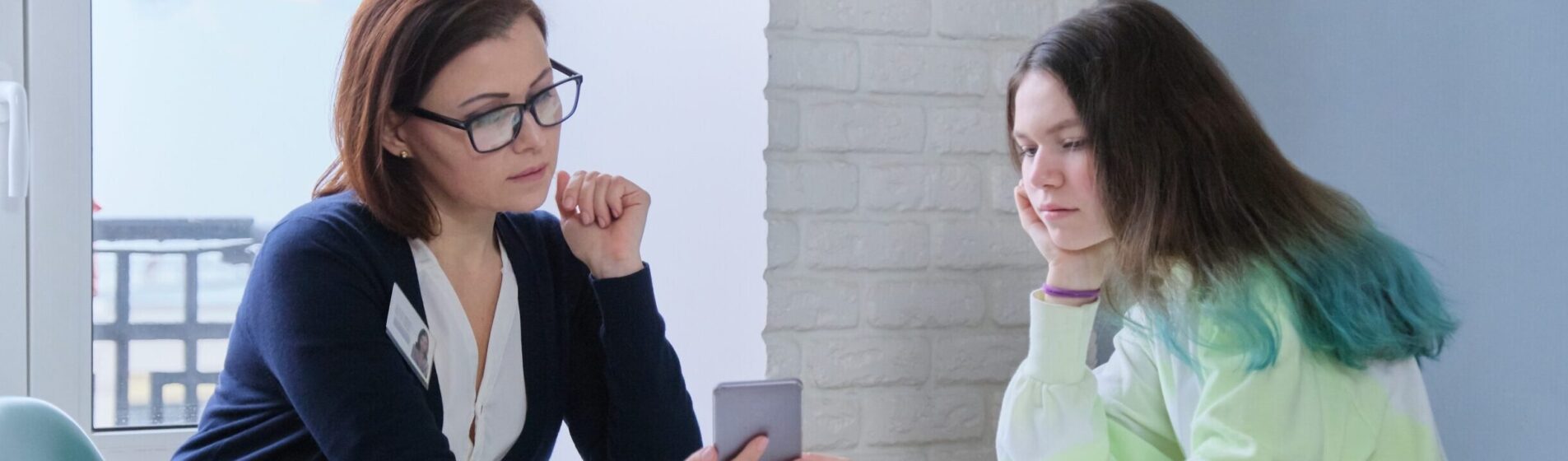 Young person and worker looking at a mobile phone