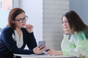 Young person and worker looking at a mobile phone