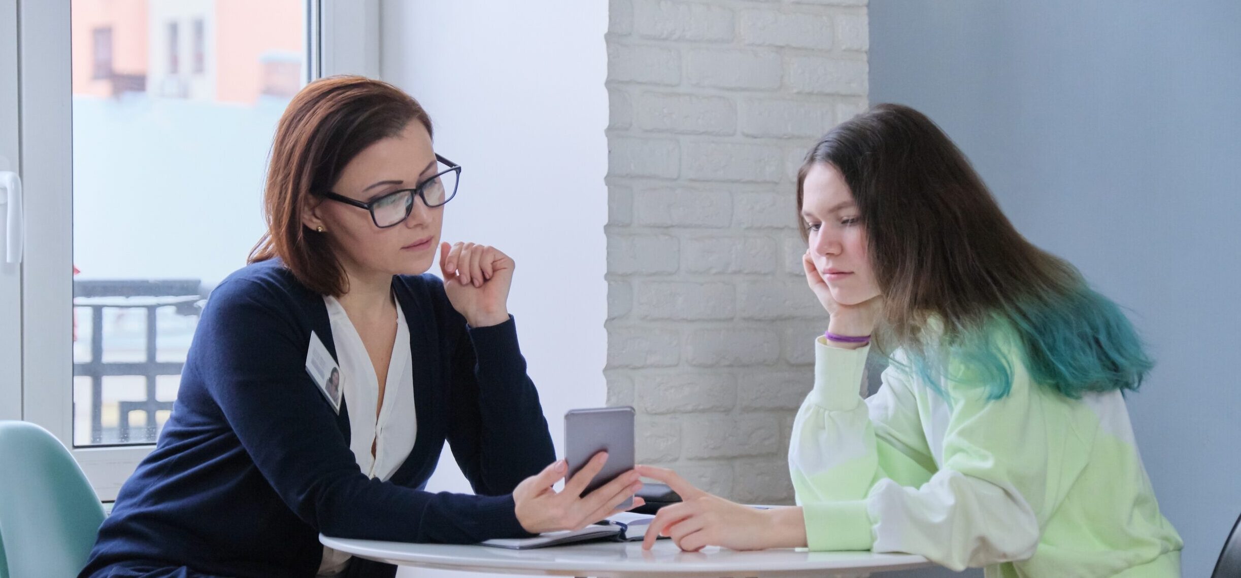 Young person and worker looking at a mobile phone