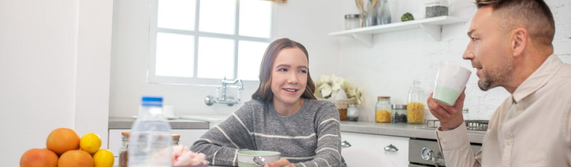 Teenage girl and male Foster Carer chatting at a table having breakfast