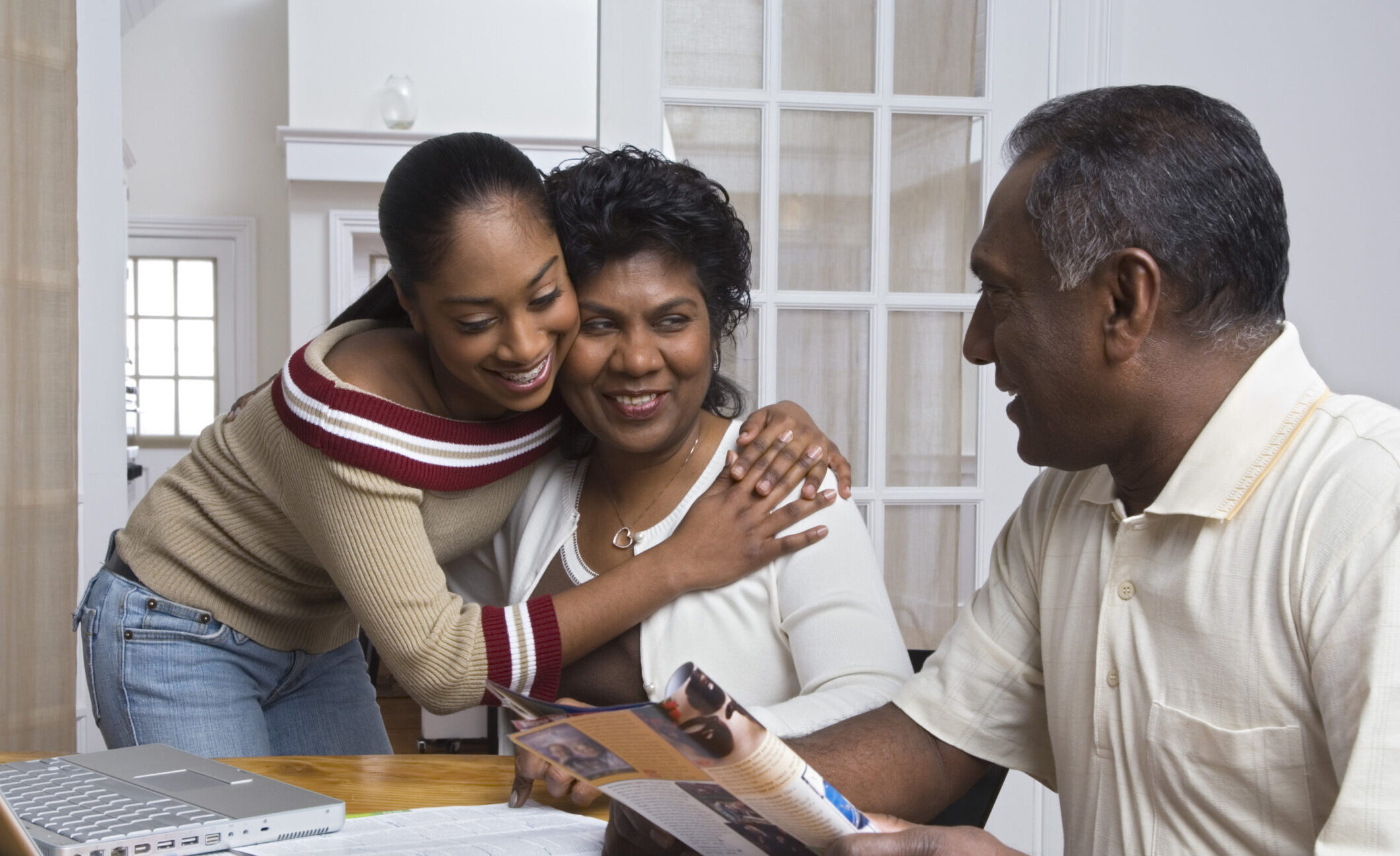 Young Person hugging her mother whilst looking at her father- everyone is happy