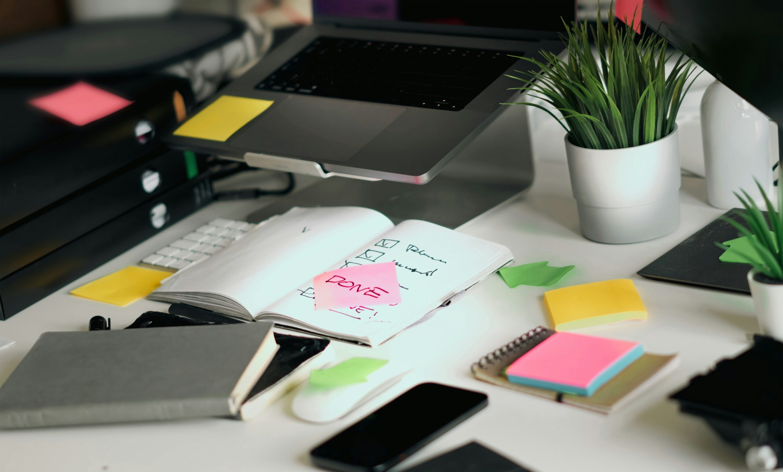 Laptop open with post its and books on a desk