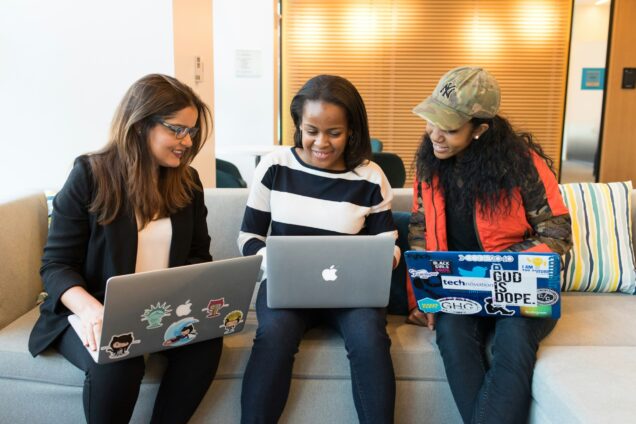 Three girls smiling each with laptop on their lap