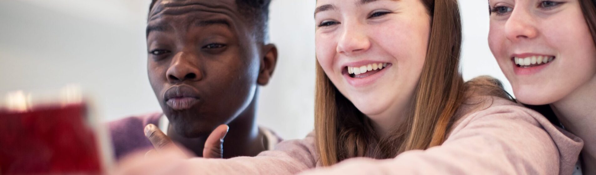 A group of teenagers posing and smiling for a selfie