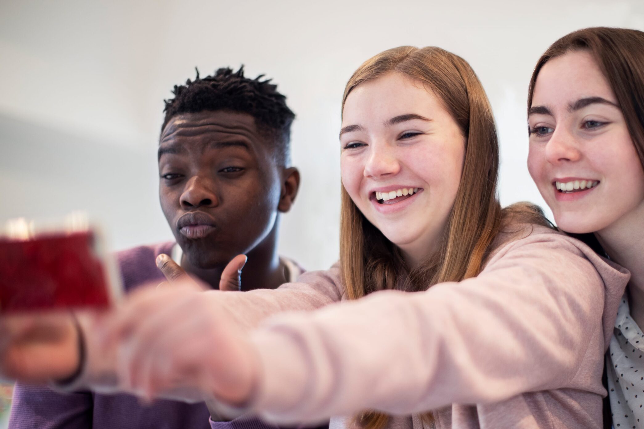 A group of teenagers posing and smiling for a selfie