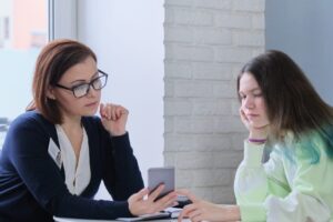 Young person and worker looking at a mobile phone