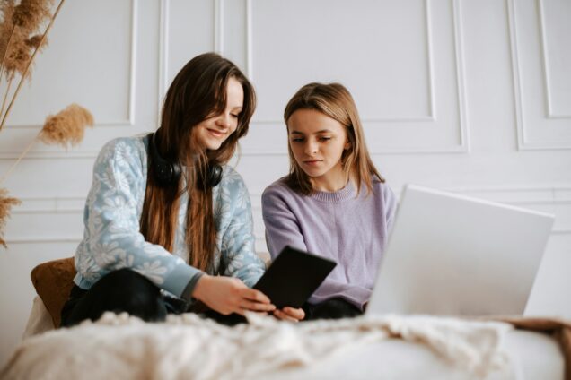 Two girls sitting looking at a tablet device