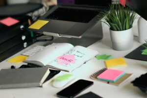 Laptop open with post its and books on a desk