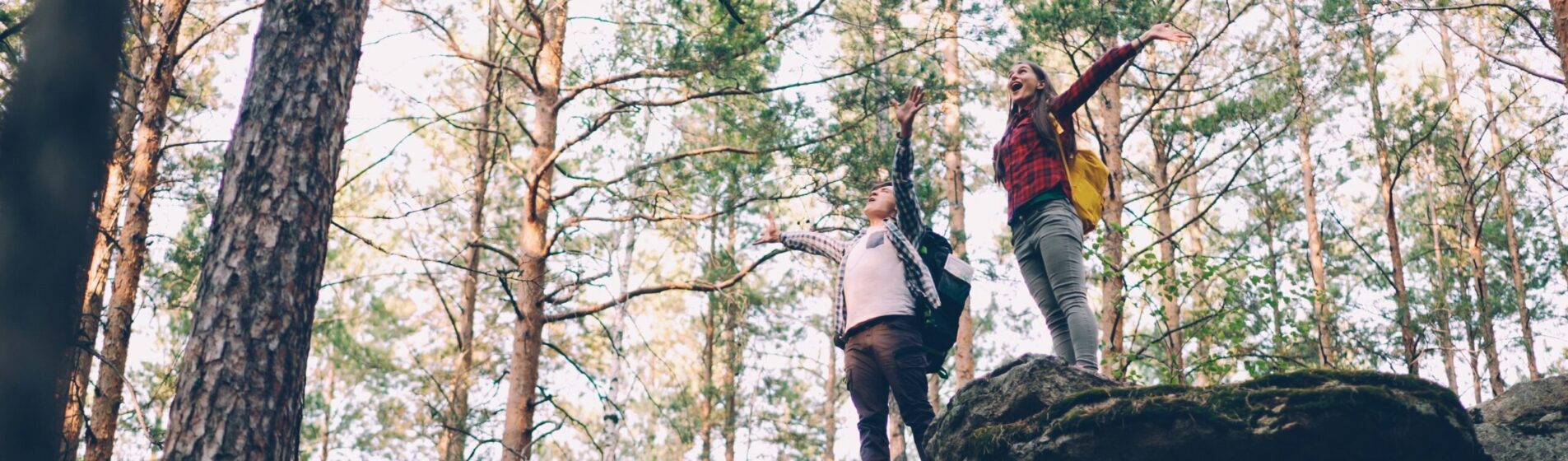 Two people in the forest with arms wide open