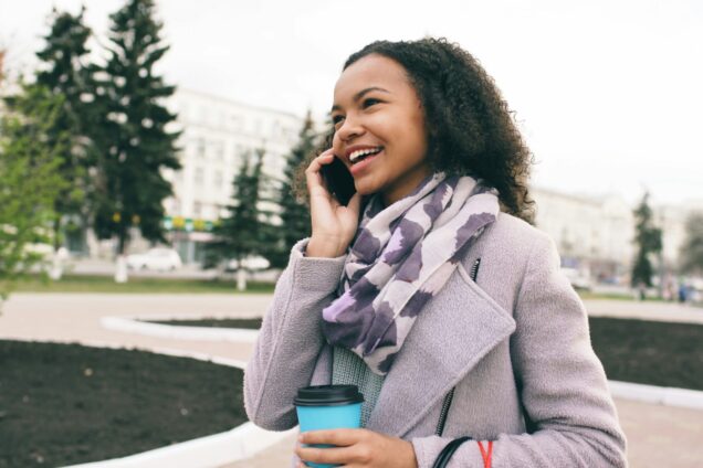 Lady smiling on the phone holding a drink