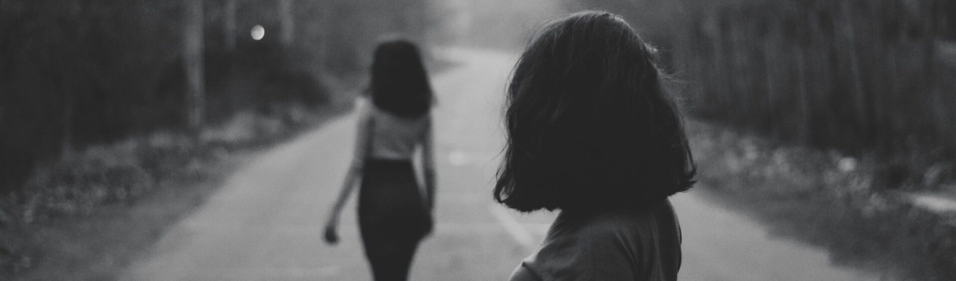 Black and white picture with a female walking away from anonther female