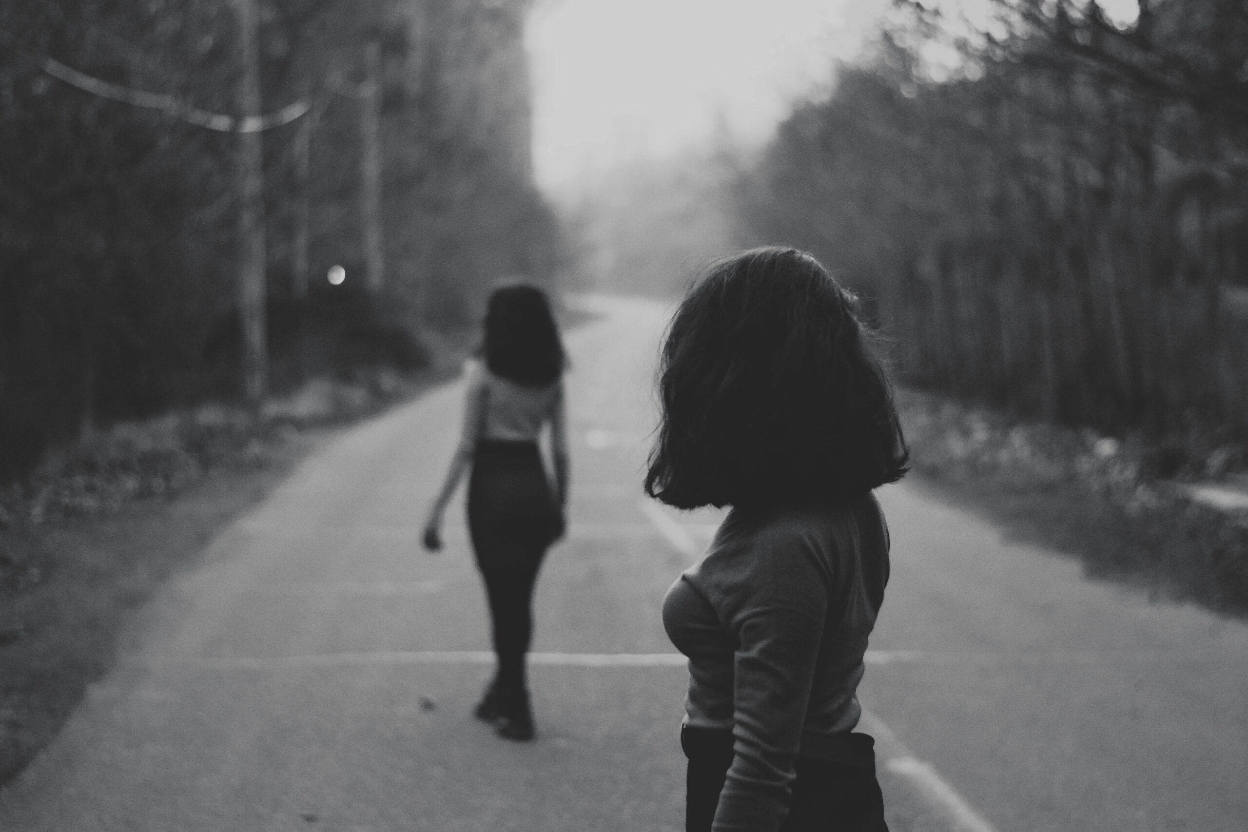 Black and white picture with a female walking away from anonther female